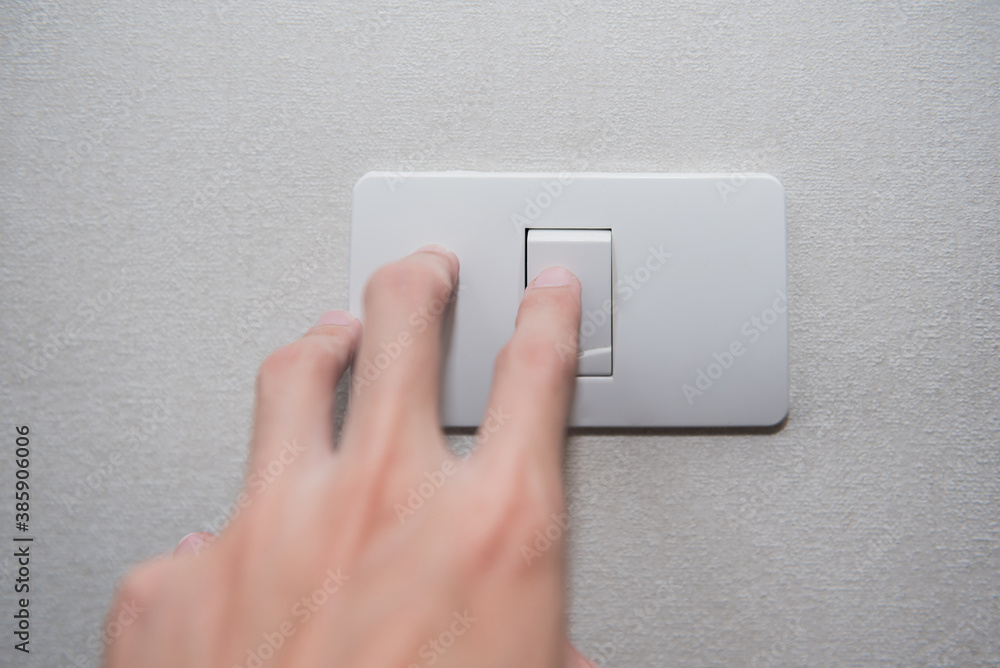 Hand with finger on light switch turn on turn off lights on white wall. Hand with finger on light switch turn on turn off lights on white wall.