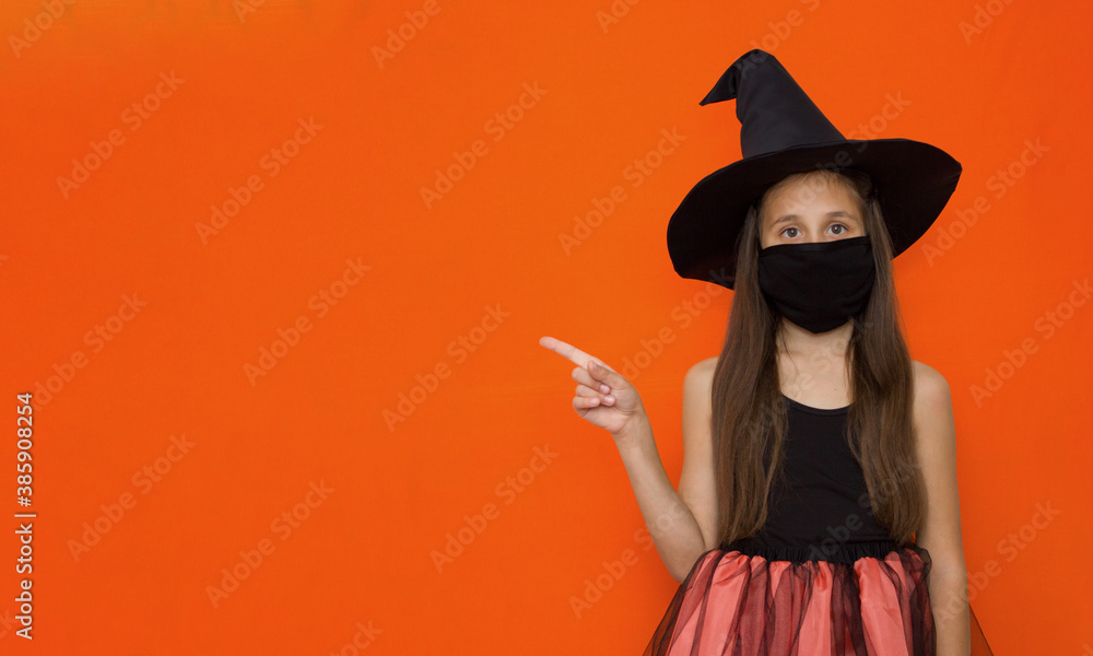 A girl with long brown hair in a hat and in a witch costume on Halloween points to advertisement, message, presentation. 