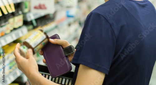 Woman Shopping at Grocery Market Pharmacy. Supermarket Shopper Doing Groceries. Female Holding Basket Trying to Decide which Products to Buy. Retail Healthcare Medicine, Vitamins, and Supplements. 