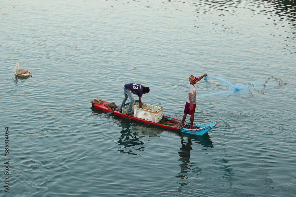 Fototapeta premium The fisherman rode a boat made of wood and threw the net in the morning to catch the fish from the lake.