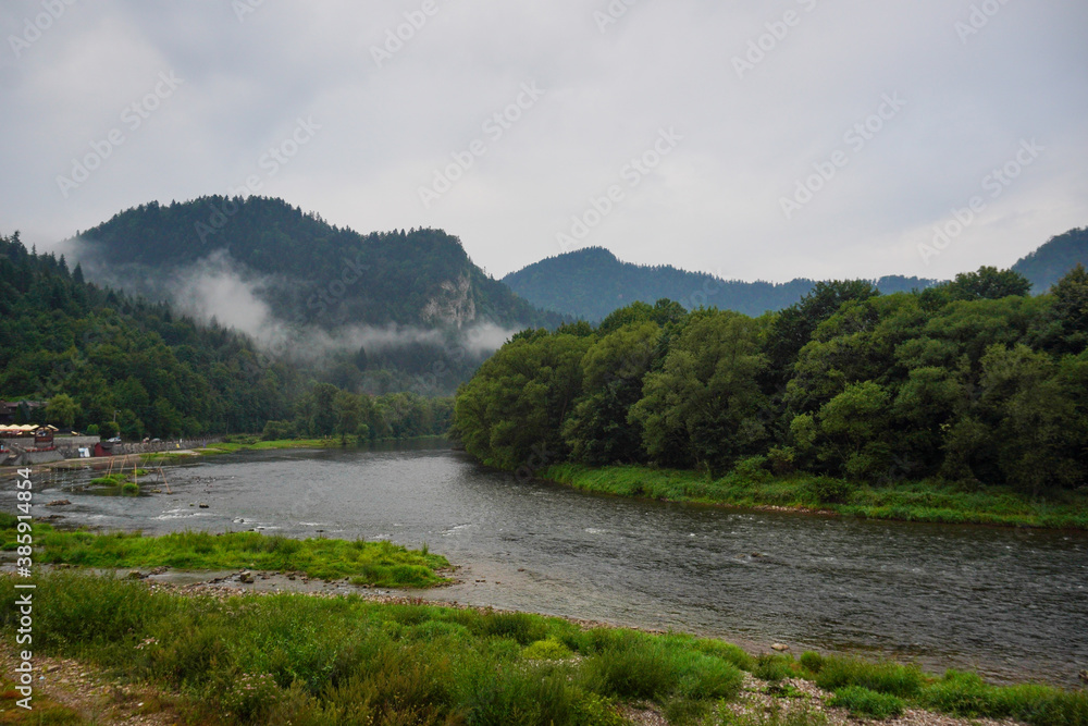 Panorama of the river and mountain view at dawn, fog over the water on a cloudy day. Landscape in Szczawnica, Poland. Beskidy mountains, three crowns trzy korony mountain, Dunajec river