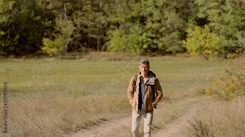 full leght portrait tourist hiker man walks along forest with backpack, walking in woods at autumn. Concept hiking, people in nature photo