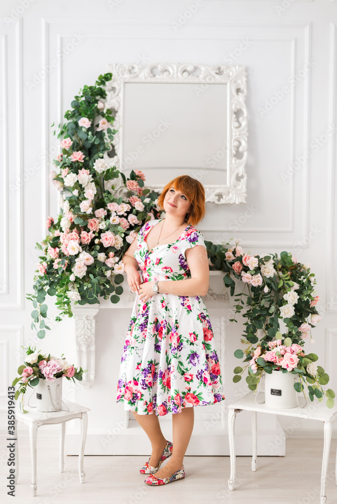 cheerful woman in a dress with flowers stands on a background of flowers cheerful woman in a dress with flowers stands on a background of flowers
