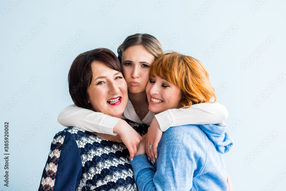 Close up portrait of a mature mother and adult daughter and teen granddaughter being close and hugging at home being happy and joyful Close up portrait of a mature mother and adult daughter and teen granddaughter being close and hugging at home being happy and joyful