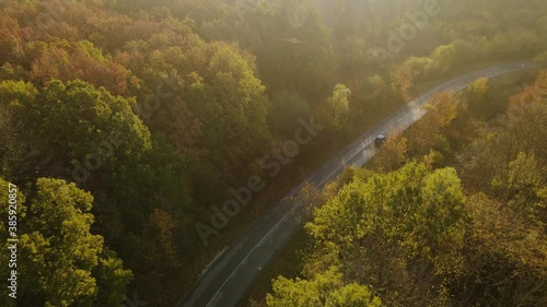 Aerial view of rural road with black car in yellow and orange au