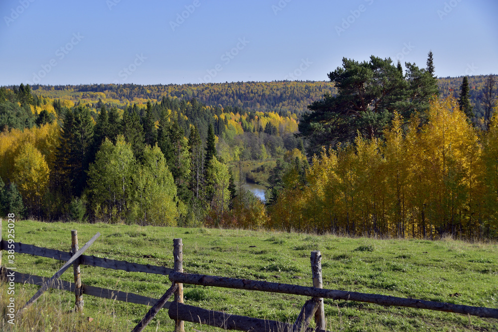 Pasture on a steep mountain above the river against the background of foothills filled to the brim with endless autumn forest. Autumn is in full swing in the foothills of the Western Urals.