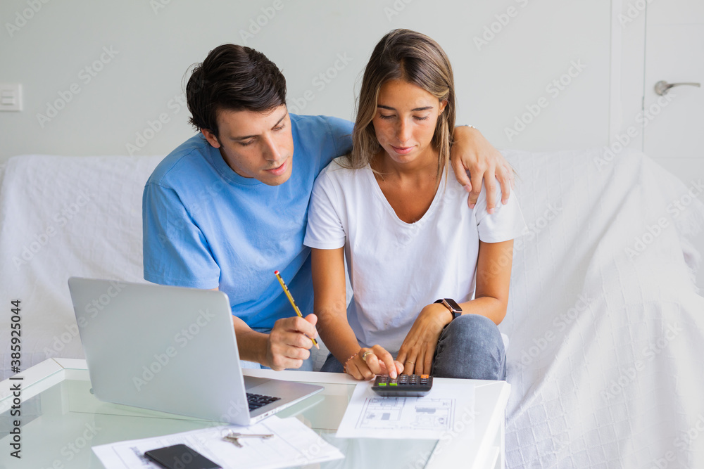 young couple sit on couch calculate expenses use easy online banking service at home, husband and wife count taxes house expenditures pay bills on internet young couple sit on couch calculate expenses use easy online banking service at home, husband and wife count taxes house expenditures pay bills on internet
