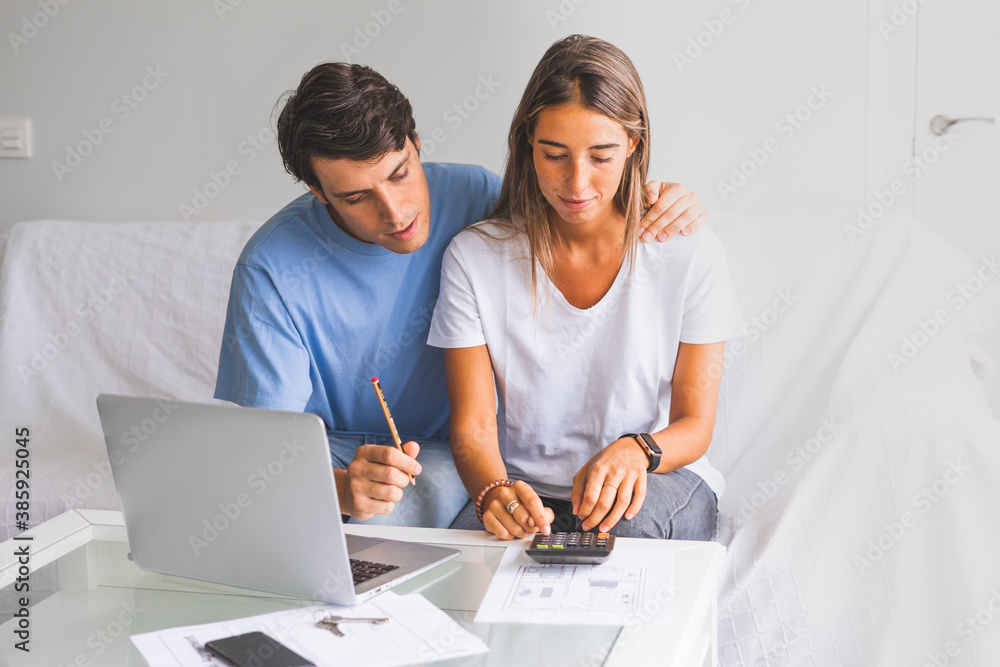 young couple sit on couch calculate expenses use easy online banking service at home young couple sit on couch calculate expenses use easy online banking service at home