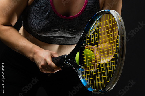 Female tennis player with racket and ball on black background © Angelov