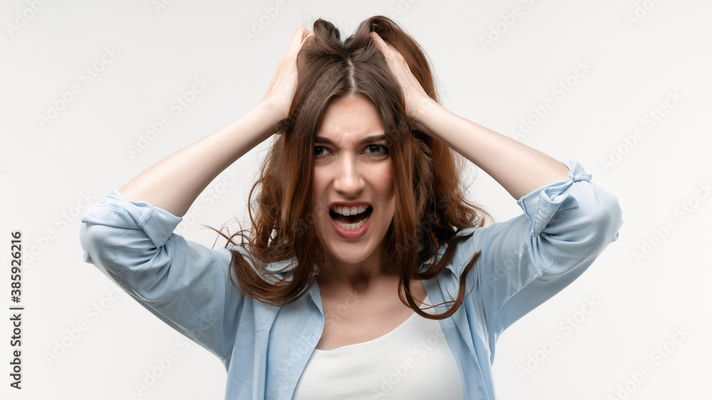Annoyed pretty girl holding her head looking at camera. Studio shot, white background. Human emotions concept Annoyed pretty girl holding her head looking at camera. Studio shot, white background. Human emotions concept
