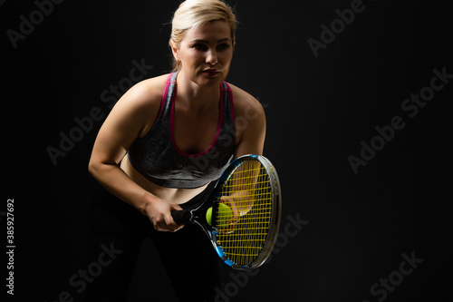 Young female tennis player posing with racket on black background © Angelov