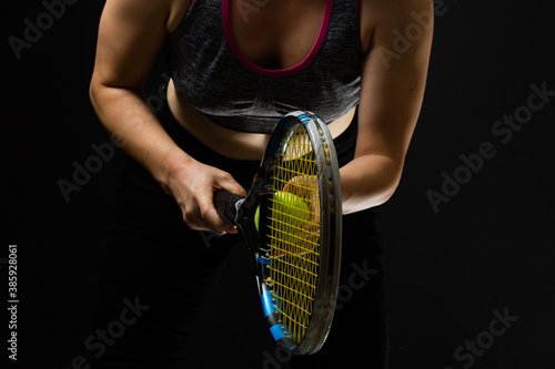 Female tennis player with racket and ball on black background © Angelov