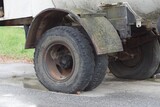 big black dirty wheels on a gray truck on the street