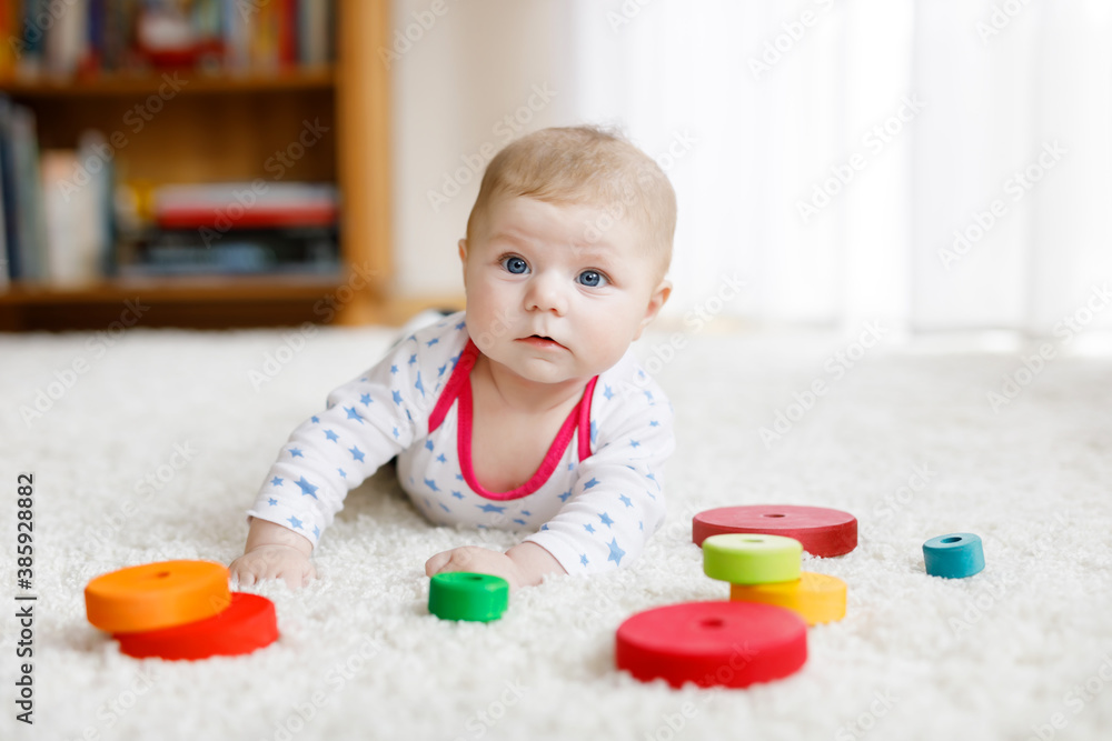 Cute baby girl playing with colorful wooden rattle toy Cute baby girl playing with colorful wooden rattle toy