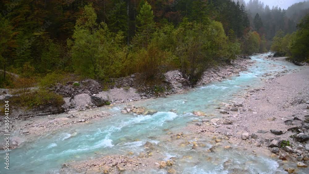 Elevated view of small river Triglavska Bistrica. Stream flows in clean pristine nature in Slovenia. Narrow Alpine valley on gloomy rainy autumn day. Static shot, real time, wide angle Elevated view of small river Triglavska Bistrica. Stream flows in clean pristine nature in Slovenia. Narrow Alpine valley on gloomy rainy autumn day. Static shot, real time, wide angle