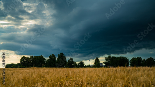 Germany, Stuttgart, Dramatic dark sky of a heavy storm front and thunderstorm above fields and tv tower Fernsehturm in summer