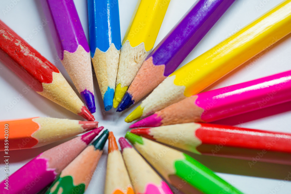 Colored and sharpened pencils lie in a circle next to each other on a white background close-up. Colored and sharpened pencils lie in a circle next to each other on a white background close-up.