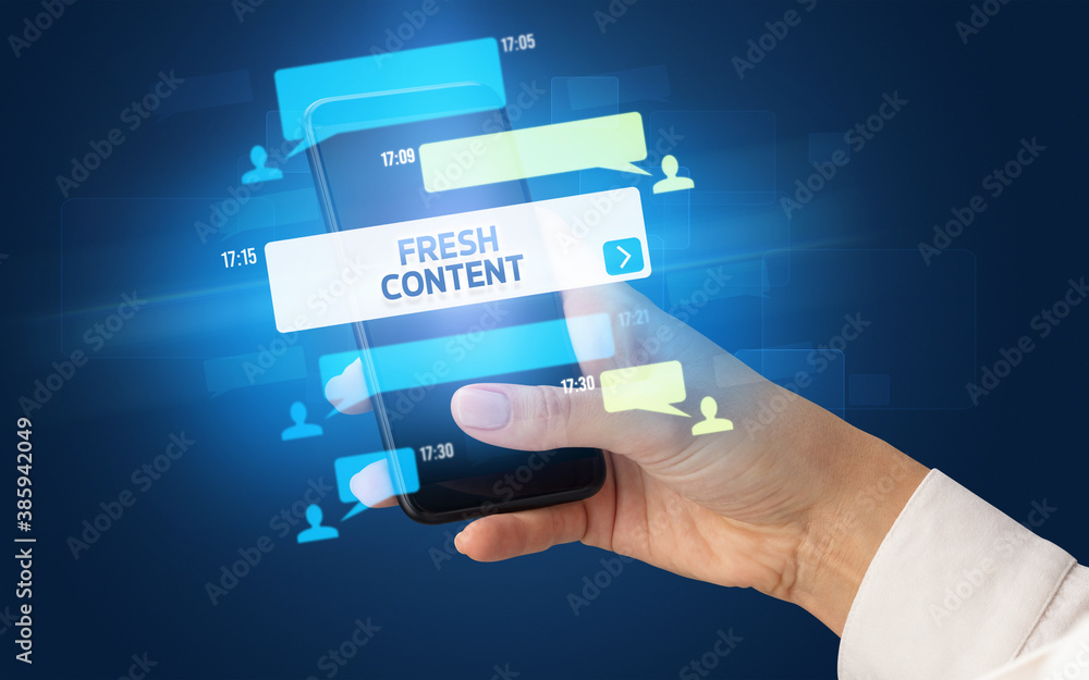 Female hand typing on smartphone with FRESH CONTENT inscription, social networking concept Female hand typing on smartphone with FRESH CONTENT inscription, social networking concept