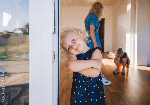 Beautiful blonde baby girl looking out from door.