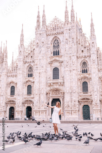 Travel tourist woman feeds doves near Duomo di Milano - the cath