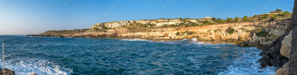 Großes Panorama einer Bucht am Mittelmeer mit steilen Felsen und Wellen in der Brandung