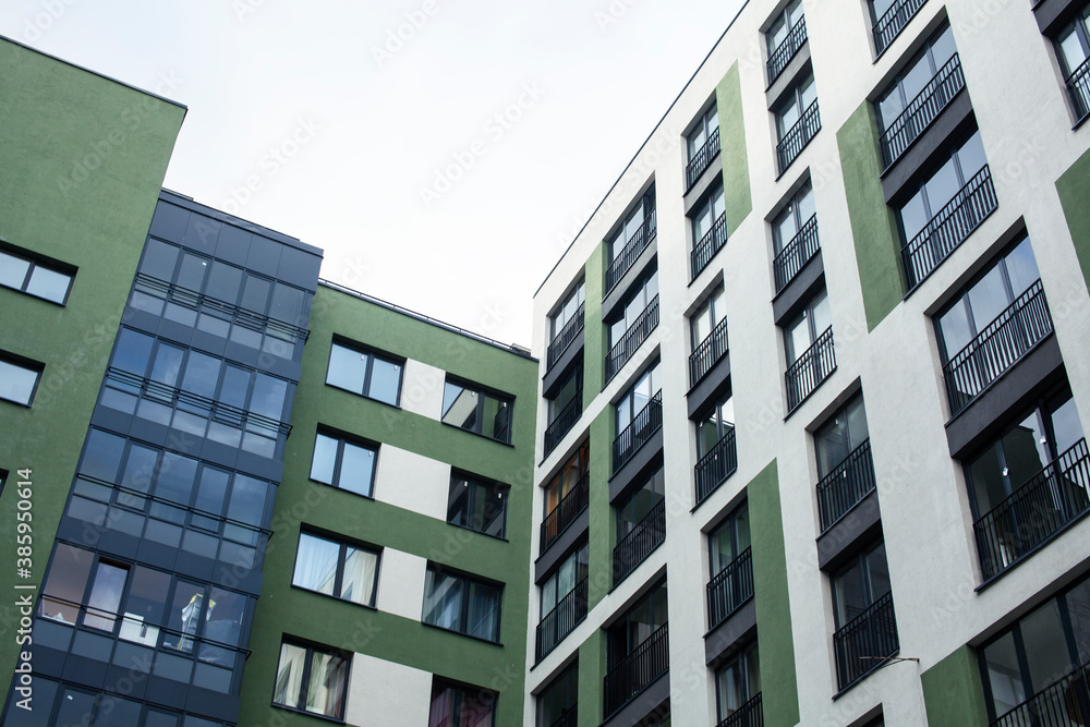 view on new modern buildings, facade corner in backjard and sky, windows on green and white wall view on new modern buildings, facade corner in backjard and sky, windows on green and white wall