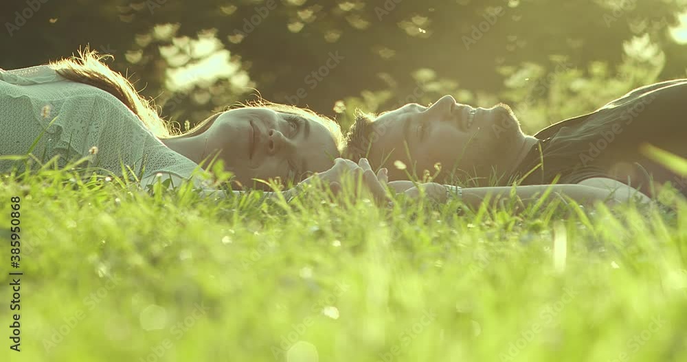 Couple lovers relaxing, hugging and kissing in the park at sunset. Love, youth, happiness concept. Health care, authenticity, sense of balance and calmness. 4K slow motion Couple lovers relaxing, hugging and kissing in the park at sunset. Love, youth, happiness concept. Health care, authenticity, sense of balance and calmness. 4K slow motion