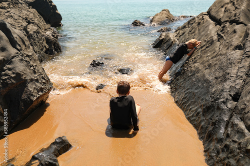 Two boys playing in water between rocks on Queensland beach photo