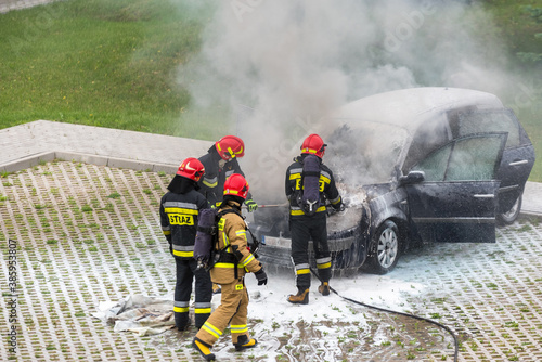 Fire brigade, putting out a burning car. Puffs of smoke near the