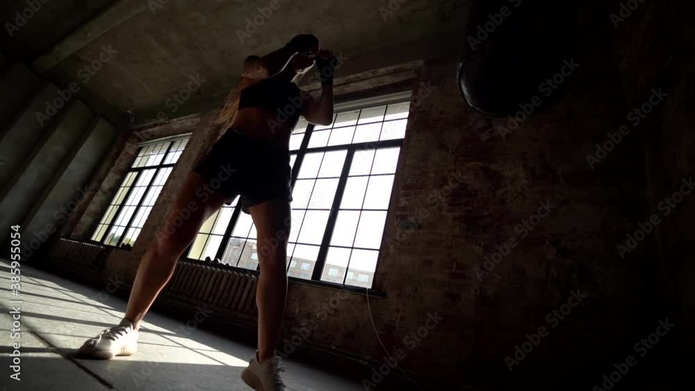 sportswoman is practicing strikes and punches of boxing, training alone in hall sportswoman is practicing strikes and punches of boxing, training alone in hall