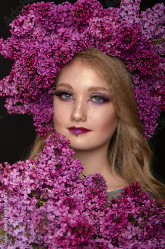 Beautiful teen girl on a dark background with beauty makeup in a smart dress with lilac