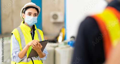 Female Inventory Manager working on digital tablet and checking quality of product at mask factory. Warehouse worker working at storage building.