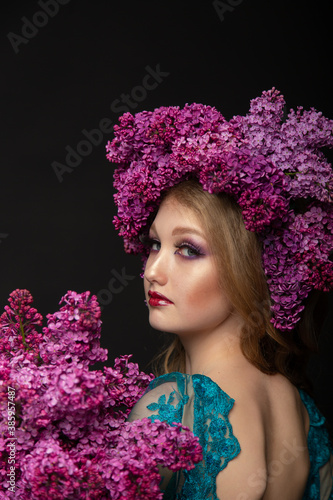 Beautiful teen girl on a dark background with beauty makeup in a smart dress with lilac