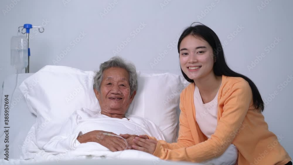 Old patient and daughter smiling at camera in hospital bed Old patient and daughter smiling at camera in hospital bed
