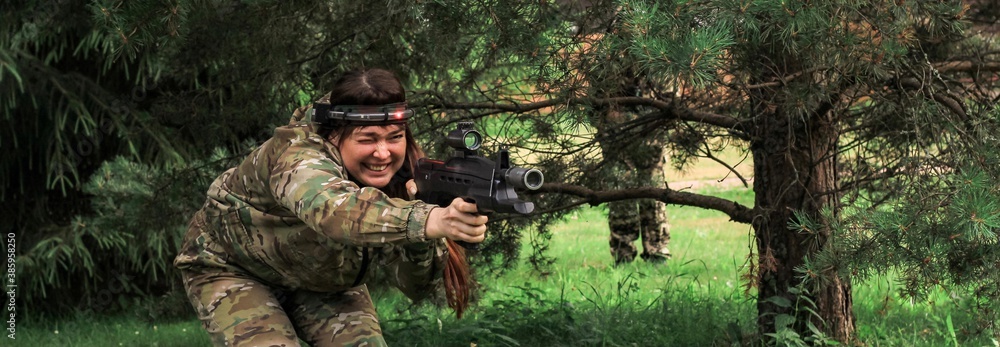 Woman playing in lasertag shooting game in open air. Weapon in the hands of people. War simulation. Banner.