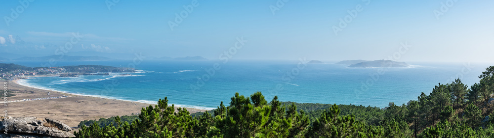Aerial view of beaches and small villages along the Ria de Pontevedra in Spain, with the Cies Islands in the background.