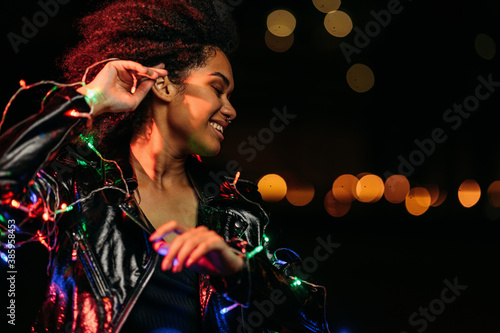 Side view of young woman posing at night in front of a city lights outdoors