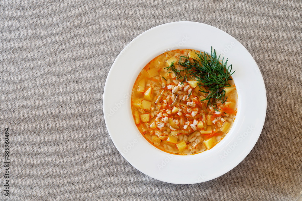 Soup with pickles, barley and vegetables on a linen tablecloth. Top view. Soup with pickles, barley and vegetables on a linen tablecloth. Top view.