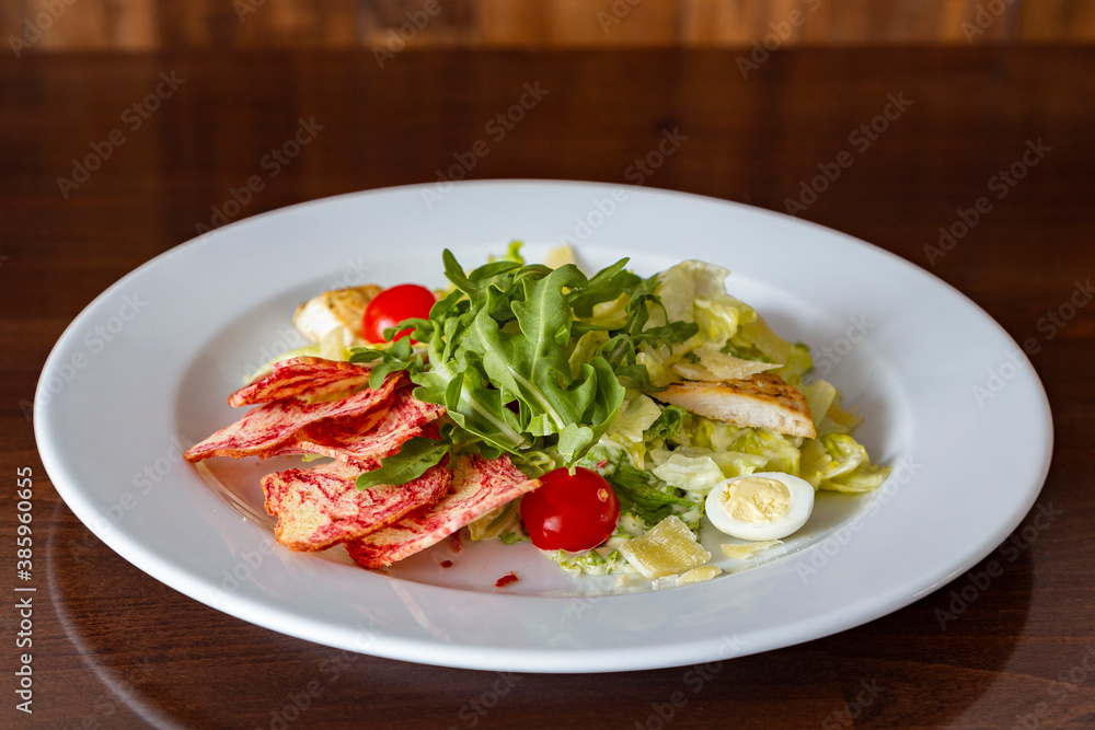 Chicken Caesar salad on the white plate with original serving. 