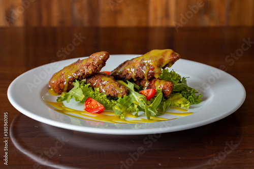 Chicken nuggets with tomatoes, herbs and sauce on a plate on a wooden background