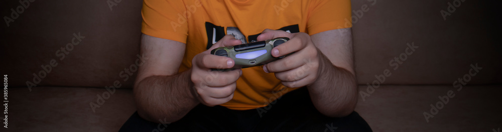 Male hands with game joystick, gamepad. The young guy is playing the console. Close up of man hands playing the video game at home. Male hands with game joystick, gamepad. The young guy is playing the console. Close up of man hands playing the video game at home.