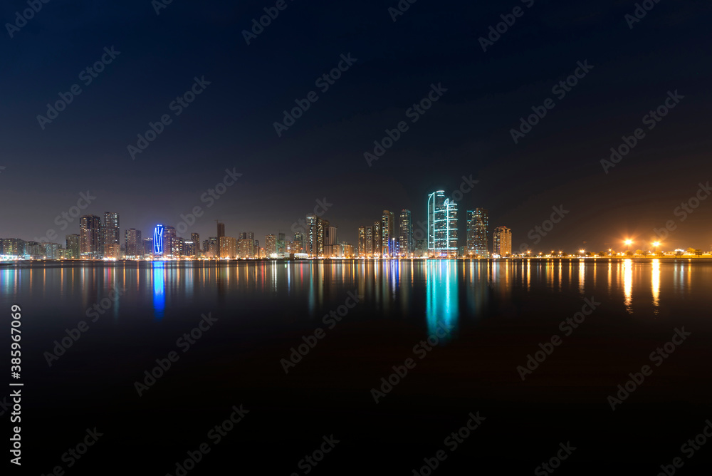 Beautiful urban city by the sea at night. A panoramic view of Sharjah skyline at night.