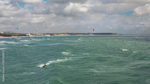Riding big waves on kitesurfing in summer. 4K Drone view of the ocean and people engaged in extreme sports, kite surfing. Beautiful clear water Aerial view people kiteboarding ride.