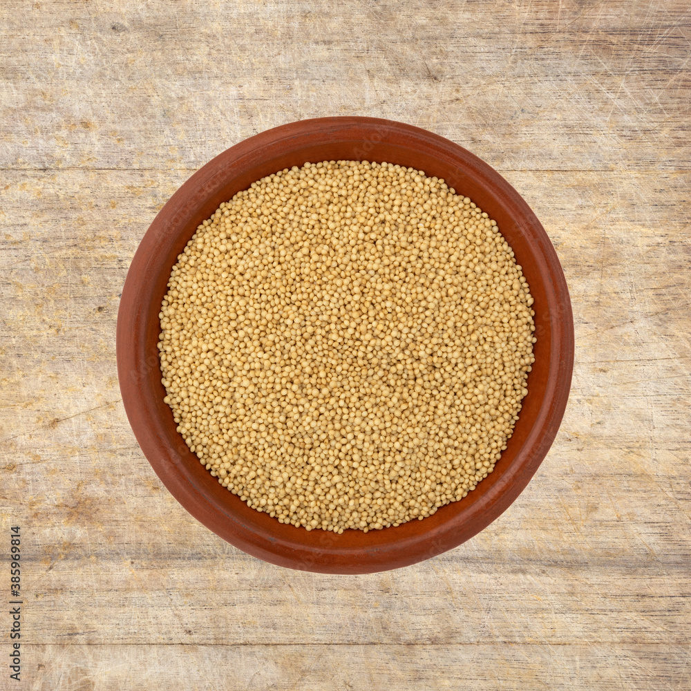 Top view of amaranth seeds in a small bowl on a wood cutting board. Top view of amaranth seeds in a small bowl on a wood cutting board.