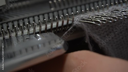 Female hands making textile on weaving machine at factory. Knitting machine Close up of weaving fabric on loom machine. Manufacturing knitted fabric on manual knitting equipment. Textile industry