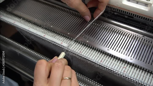 Female hands making textile on weaving machine at factory. Knitting machine Close up of weaving fabric on loom machine. Manufacturing knitted fabric on manual knitting equipment. Textile industry