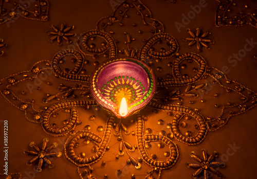 Obraz na plátne A traditional indian earthen lamp glowing on a golden luxurious embroidered back