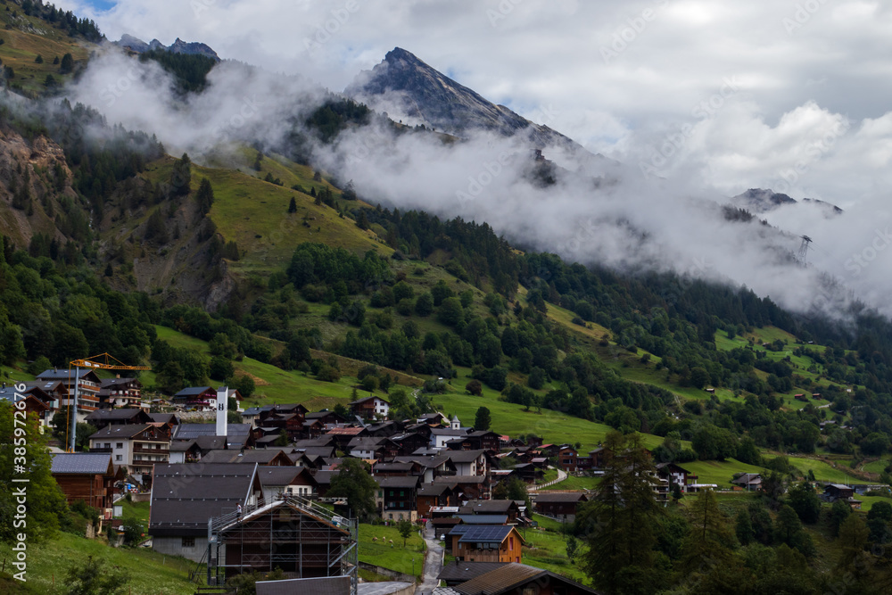 Small village in a valley of the Valais Alps of Switzerland on a misty summer day. 