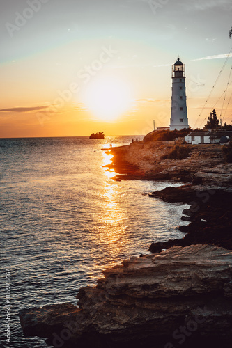 old lighthouse at sunset. a sunken ship in the distance. vertical photo © John