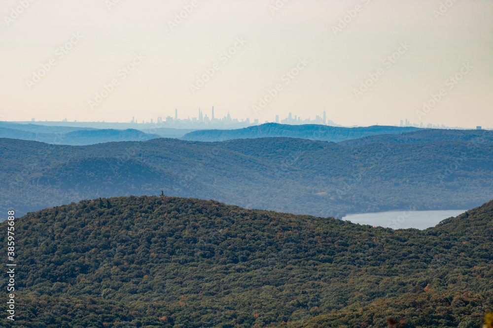 Fototapeta premium Hazy New York City skyline far in the distance over the Hudson Highlands, seen from the Mount Beacon Fire Tower